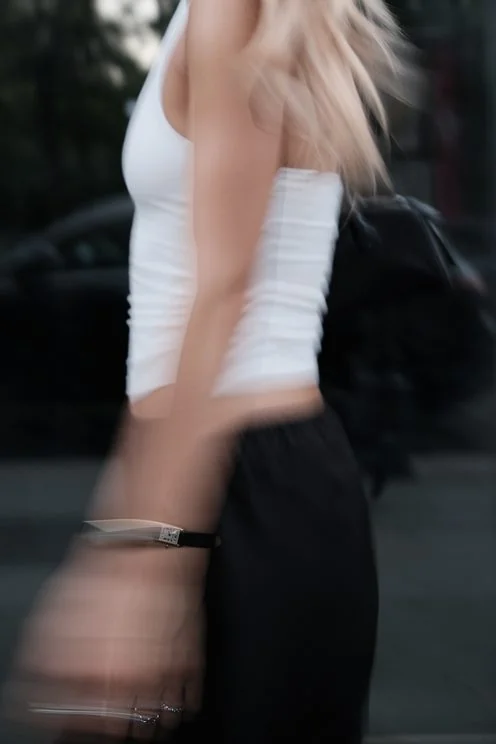 Louisa Reiter in a white top at dusk, motion-blurred street scene with a wristwatch