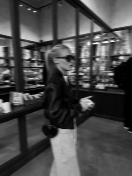 Louisa Reiter in a boutique, black-and-white motion-blurred scene with sunglasses