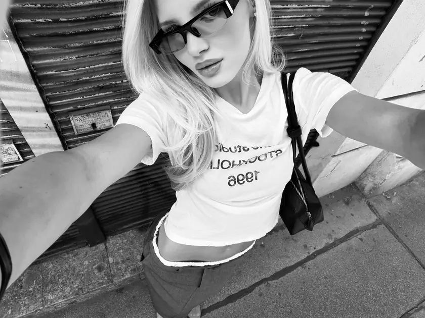 Black-and-white selfie of Louisa Reiter in sunglasses and a white T-shirt in front of a corrugated metal shutter