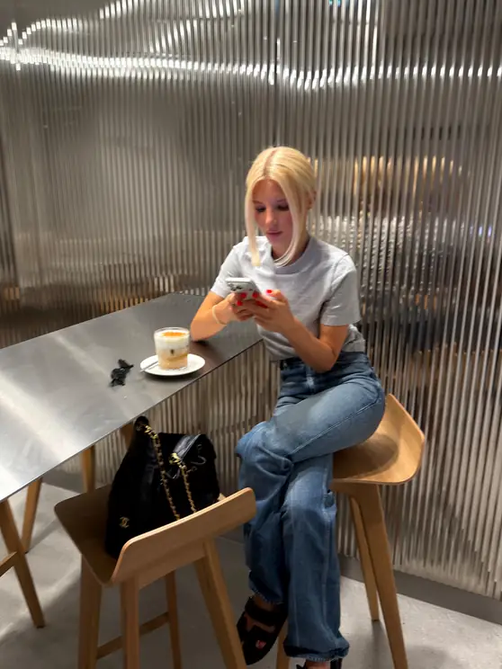 Louisa Reiter sitting at a cafe counter with a coffee, looking at her phone
