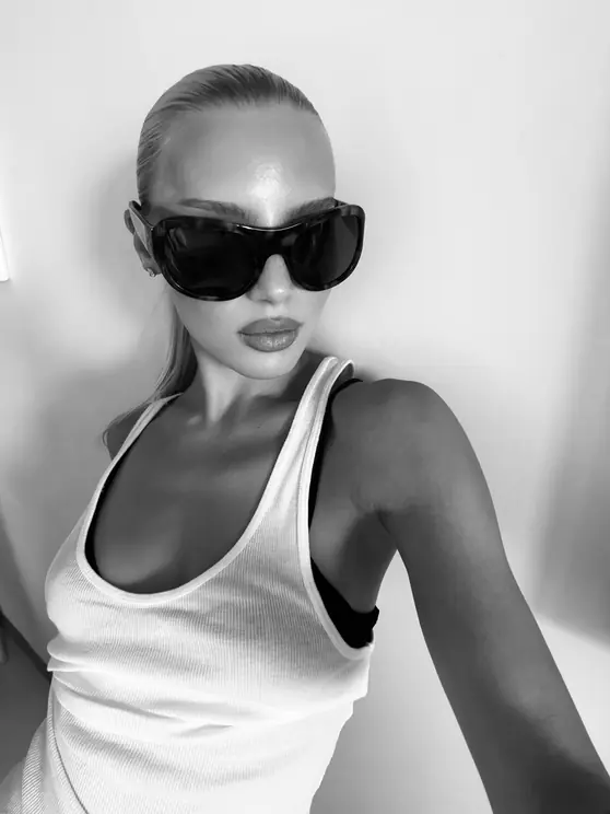 Black-and-white portrait of Louisa Reiter in oversized sunglasses and a white tank top