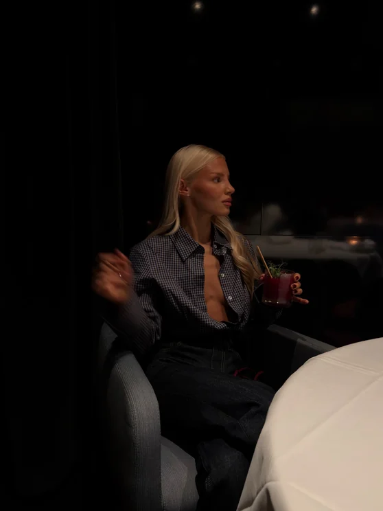 Louisa Reiter with a drink at a dimly lit restaurant table in the evening